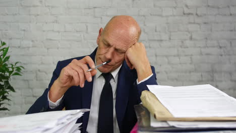 bored-businessman-with-piles-of-paperwork-on-his-desk