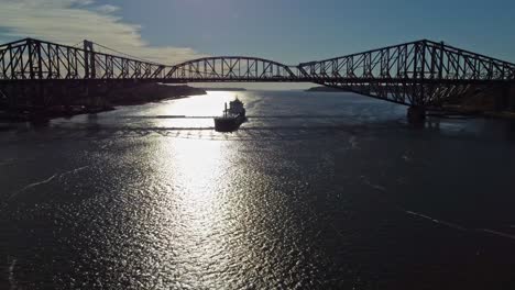 Drone-shot-going-backward-while-a-cargo-boat-is-travelling-under-Quebec-bridge