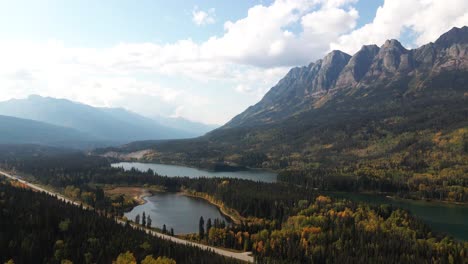 Ehrfurchtgebietende-Luftschwenk-Zoomaufnahme-Des-Mount-Robson-Provincial-Park-Im-Herbst-Am-Yellowhead-Lake-An-Einem-Tag-Mit-Einer-Mischung-Aus-Sonne-Und-Wolken-Mit-Yellowhead-Highway-Davor-Und-Bunten-Bäumen