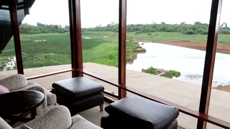 Panning-shot-from-inside-a-safari-resort-hotel-looking-out-onto-a-fresh-river