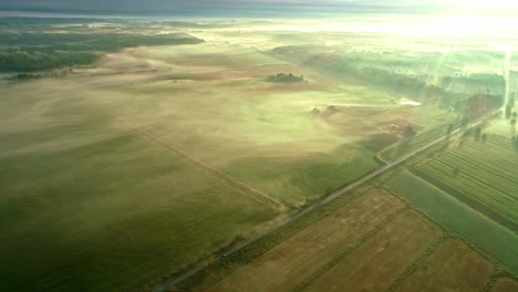 Drone-shot-of-mist-and-cloud-over-farmland-in-early-morning-sunrise