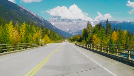 fantastic-dolly-forwards-GoPro-wide-shot-towards-Mount-Robson-on-Yellowhead-Highway-in-BC-in-Canada-on-a-sunny-day-surrounded-by-forest-with-yellow-and-green-trees-and-mountain-peaks-and-Cars-driving