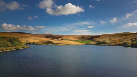 Sweeping-aerial-drone-video-footage-taken-near-Saddleworth-moor-of-a-series-of-Lakes,-Reservoirs,-set-against-a-backdrop-of-moorland-and-woodlands