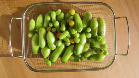 Green-organic-tomatoes-ripening-inside-in-a-metal-basket-in-sunlight