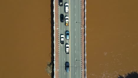 Top-down-aerial-drone-shot-over-cars-stuck-on-bridge-over-flooded-river