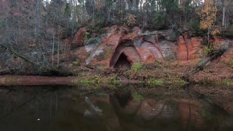 Angels-Cave,-a-Red-Sandstone-Cliff-in-a-Shape-of-Angel-Wings,-at-the-River-Salaca-in-Skanaiskalns-Nature-Park-in-Mazsalaca,-Latvia,-Autumn-Time