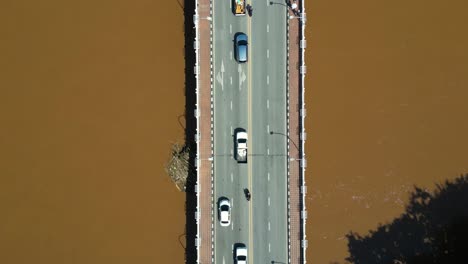 Overhead-aerial-drone-shot-of-cars-driving-on-bridge-on-flooded-river