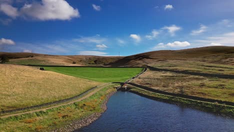 Aerial-drone-video-footage-taken-at-Ogden-Saddleworth-moor-in-Oldham,-England-of-a-series-of-Lakes,-Reservoirs,-set-against-a-backdrop-of-moorland,-woodlands-and-blue-sky's