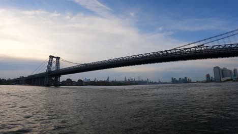 Boat-crossing-under-large-bridge-in-Manhattan-New-York
