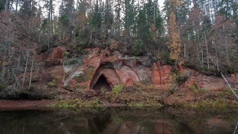 Angels-Cave,-a-Red-Sandstone-Cliff-in-a-Shape-of-Angel-Wings,-at-the-River-Salaca-in-Skanaiskalns-Nature-Park-in-Mazsalaca,-Latvia,-Autumn-Time