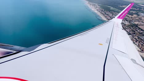 Wizzair-aircraft-wing-flying-from-Rome-airport-over-coastline,-Italy