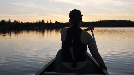 Woman-paddling-a-canoe-into-beautiful-sunset-reflections-in-The-Boundary-Waters