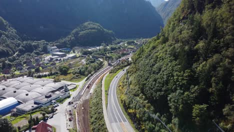 Road-E16-and-railway-from-Bergen-passing-town-of-Dale-with-Dale-of-Norway-company-industrial-buildings-below-road-to-the-left-and-Eviny-energy-company-in-mountain-background---Aerial