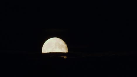 Dramatic-low-moon-rise-through-thin-cloud-layer-time-lapse-strong-air-disturbance