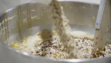 Slow-motion-close-up-shot-of-a-mixing-pot-with-various-ingredients-for-homemade-candy-being-mixed-into-a-mass-or-batter