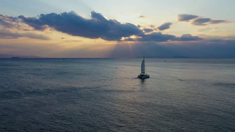 Aerial---Catamaran-cruising-in-Vouliagmeni,-Greece-at-sunset
