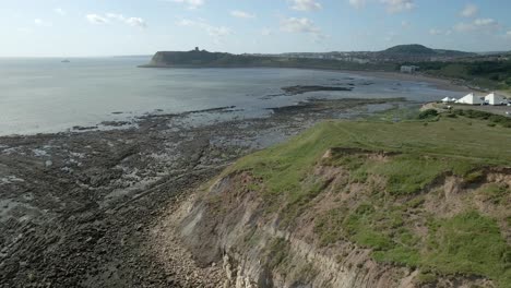 Ascending-Aerial-view-of-North-bay,-Scarborough,-North-Yorkshire-with-cliffs,-coastline,-ocean,-and-castle