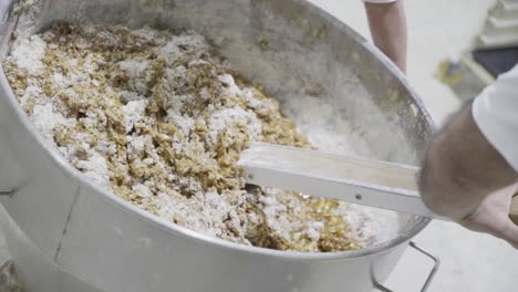 Slow-motion-handheld-shot-of-a-dough-mass-for-candy-being-mixed-by-a-baker-in-candy-factory