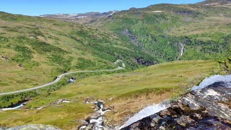 Naturaleza-Salvaje-Con-La-Carretera-Rv13-Cruzando-La-Montaña-Vikafjell-En-Noruega-Vista-Desde-La-Idílica-Ladera-De-La-Montaña-Con-Un-Río-Fresco-Y-Nítido-Que-Pasa-En-Primer-Plano-Cerca-De-La-Cámara---Estático