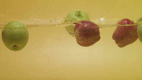 Aufnahme-Eines-Haufens-Roter-Und-Grüner-Äpfel,-Die-Ins-Wasser-Gefallen-Sind
