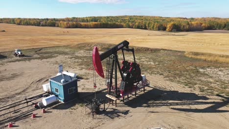 aerial-drone-pan-shot-of-oil-black-and-red-pump-jack-pumping-oil-on-a-field-in-Alberta-Canada-on-a-sunny-day