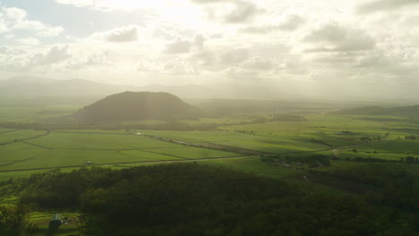 Aerial-Drone-Of-Sunlight-Rays-Through-Clouds-On-Green-Mountain-At-Sunset,-4K-Australia