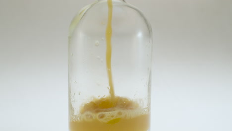 Close-up-shot-of-pouring-apple-juice-into-a-glass-bottle