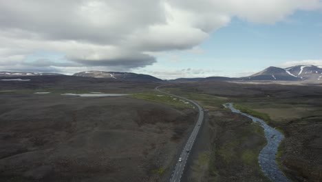 drone-flying-high-over-a-couple-of-cars-on-a-road-somewhere-in-the-backcountry-of-Iceland-in-4k