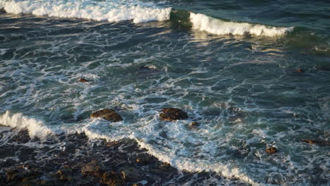 Close-Up-Of-White-Wash-Ocean-Waves-Crashing-Onto-Rocky-Beach-Shore,-4K