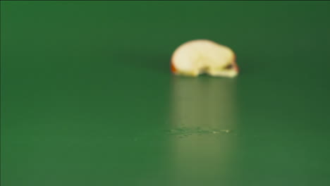 Red-apple-falling-and-breaking-into-pieces-on-a-green-background