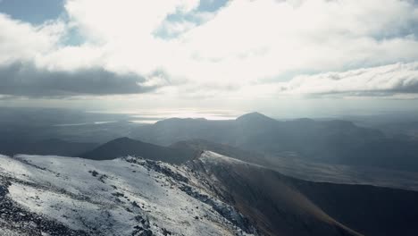 Increíble-Toma-Aérea-De-Rayos-De-Sol-Que-Emergen-A-Través-De-Las-Nubes-Sobre-Las-Montañas-En-Snowdonia,-Reino-Unido