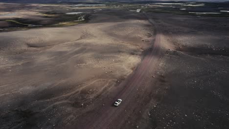 Drone-Siguiendo-Un-Auto-Plateado-Filmado-Desde-El-Lado-Derecho-Conduciendo-Fuera-De-La-Carretera-En-El-Campo-Lunar-De-Islandia-En-4k