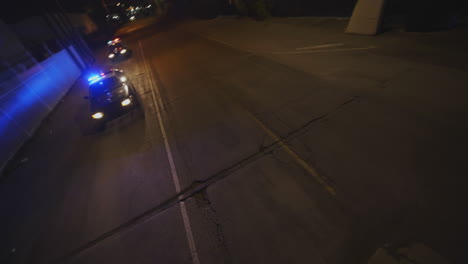 FPV-drone-shot-of-two-police-cars-responding-with-flashing-lights-at-night