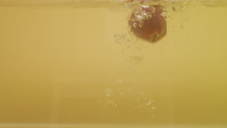 Shot-of-a-red-apple-droppied-in-container-with-water