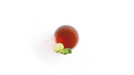 lemon-tea-in-a-transparent-glass-cup-with-sliced-lemon-mint-leaves-in-white-background-rotating-side-shot