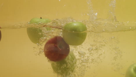 Shot-of-a-bunch-of-apples-with-different-colors-dropped-in-water