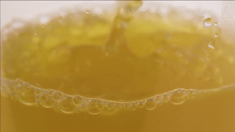 Close-up-shot-of-apple-juice-bubbling-while-pouring-in-a-glass-bottle