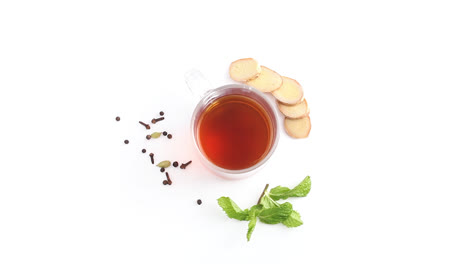 lemon-tea-in-a-transparent-glass-cup-with-whole-and-sliced-lemon-in-white-background-rotating-top-shot