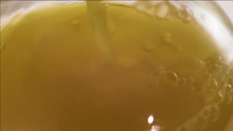 Close-up-shot-of-apple-juice-bubbling-while-pouring-in-a-glass-bottle