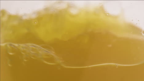 Close-up-shot-of-apple-juice-pouring-in-a-glass-bottle