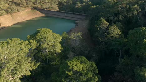 Drone-Descendiendo-Sobre-Densos-árboles-Forestales-En-La-Orilla-De-La-Represa-El-Calaque-En-Jalisco,-México-Durante-La-Estación-Seca