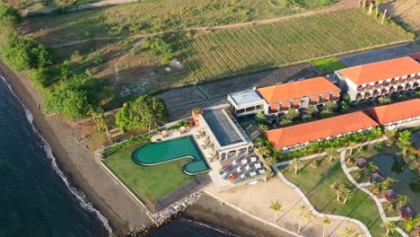Vista-Aérea-De-Un-Hermoso-Resort-Junto-A-La-Piscina-En-La-Costa-De-La-Playa-De-Lovina-En-Bali,-Indonesia,-Al-Atardecer