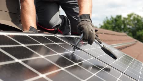 Professional-technician-screwing-a-solar-panel-to-a-roof-in-slow-motion-in-daylight