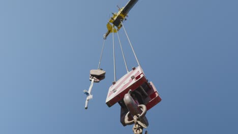 Low-angle-upward-view-of-a-static-lifting-load-crane-and-a-sunny-blue-sky