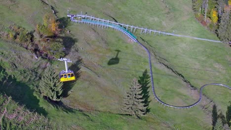 Aerial-shot-of-a-cable-car-moving-from-the-mountain-down-to-the-ground-station-on-Kronberg-Appenzell-in-the-Swiss-alps