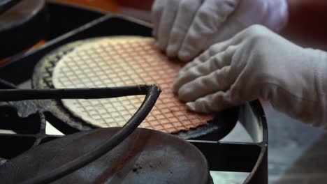 Close-up-shot-of-hands-open-up-the-iron-cast-press,-and-flipping-side-of-the-crepe-and-pressing-down-again,-in-preparation-of-fresh-ice-cream-waffle-cone