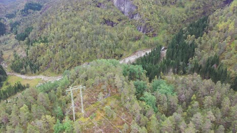 High-voltage-power-lines-passing-in-Vaksdal-mountains-Norway---Small-Markaani-river-powerplant-intake-down-in-valley-to-the-right