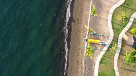 Luftbild-Von-Oben-Nach-Unten-Auf-Das-Indonesische-Jukung-Boot,-Das-An-Der-Wunderschönen-Küste-Von-Lovina-Bali,-Indonesien,-Gestrandet-Ist,-Während-Blaue-Ozeanwellen-Bei-Sonnenuntergang-Abstürzen