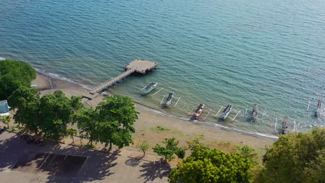 Luftaufnahme-Von-Jukung-Booten,-Die-An-Der-Küste-Von-Lovina-Beach-Verankert-Sind,-Mit-Sonne,-Die-Sich-An-Einem-Sonnigen-Tag-In-Bali,-Indonesien,-Widerspiegelt