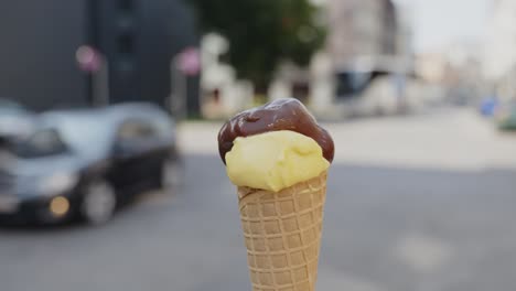 Focused-close-up-of-a-vanilla-and-chocolate-ice-cream-cone-being-spun-by-a-person-on-the-street